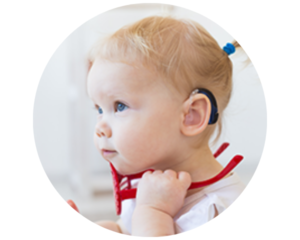 A young child with a cochlear implant holds a red toy, looking attentively to the side.